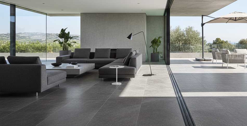 Espace de vie avec grès cérame grand format effet pierre volcanique, transition intérieur-extérieur sans joints apparents